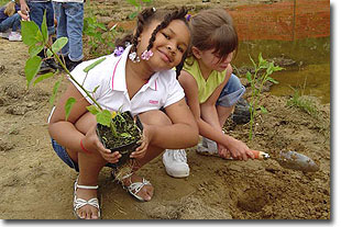 2 young girls planting native plants in their school yard