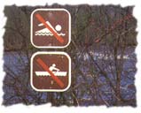 [Signs for no swimming and no boating in front of a river.]