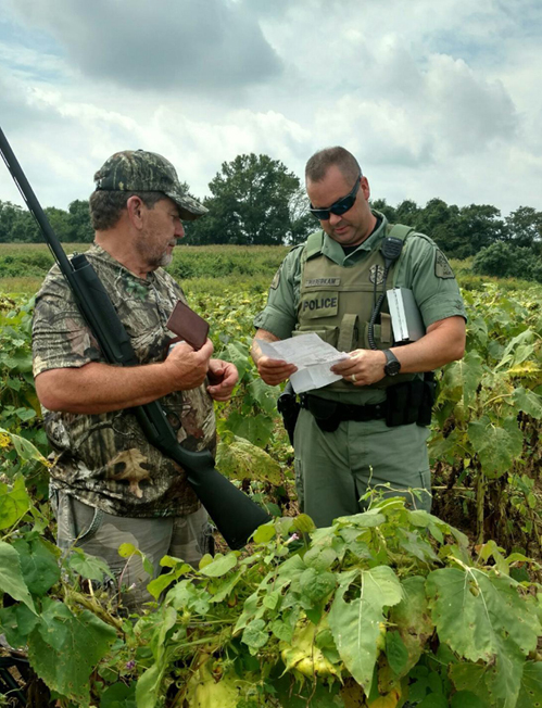Natural Resources Police Officer checking a hunter’s license.