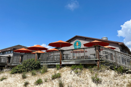 View from the beach, open deck seating with umbrellas perched on the dunes