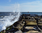 Waves hitting over a jetty of rocks