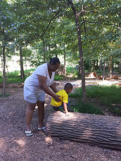 Woman helping child climb onto a log