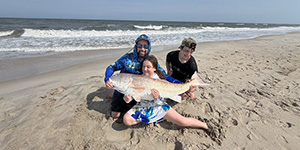 Young Ella Hoenke gets some help holding on to a large red drum for a quick picture that she caught and released at Assateague Island. 
