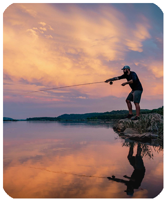 Angler fly fishing at sunrise