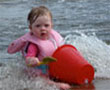 image of child in beach water with red bucket