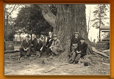 Early Forestry Board Meeting. Members sitting outside next to a big tree.