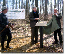 Francis Zumbrun looks on while Jim Garrett and Kirk P. Rodgers unveil the Centennial Plaque at the Garrett-Potomac State Forest