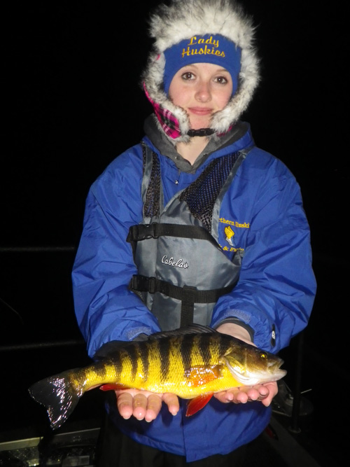 Woman dressed in winter clothes holding a yellow perch.