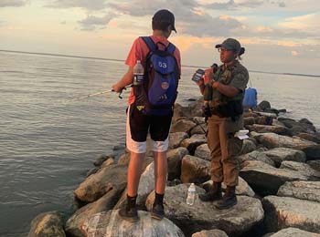 NRP officer on a jetty checking a fishing license