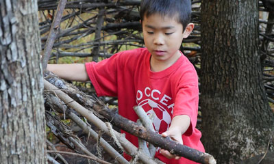 Kid playing with branches, making a wall