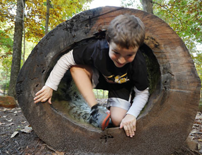 Boy coming out of the end of a hollowed out log