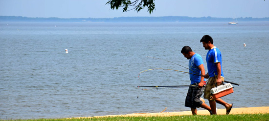 People with fishing poles walking along the waterfront