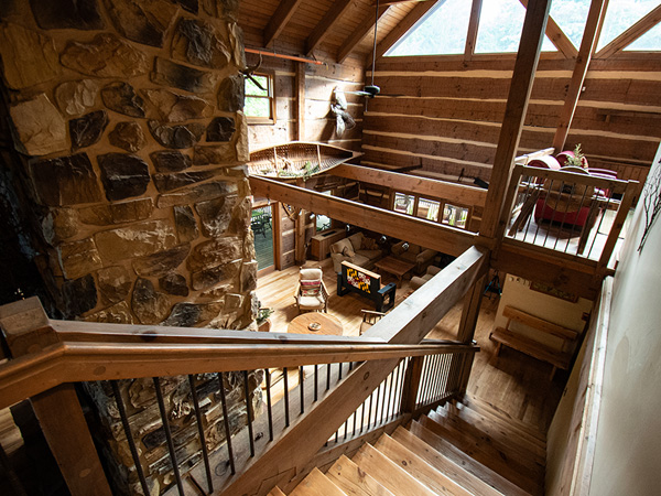 view of the lodge from the upstairs, large great room, fireplace and loft all done is classic log cabin style