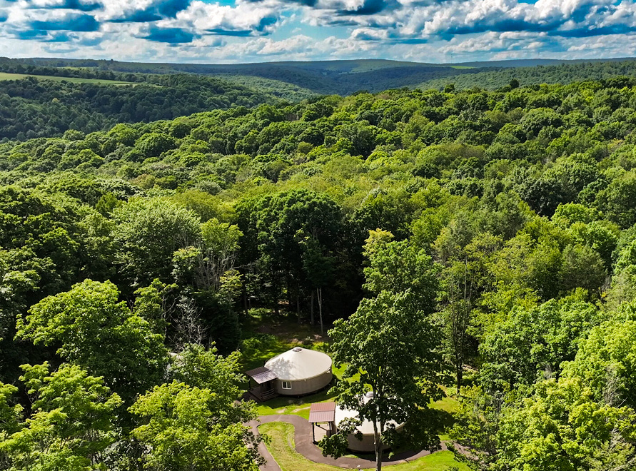 Yurts nestled in the woods of Savage River State Forest. You can see the mountain ridge and puffy white clouds off in the distance
