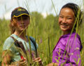 Two young girls standing behind tall grass.