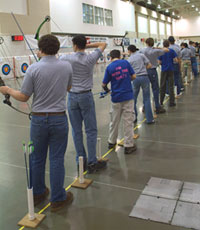 Several archery students straddling the shooting line